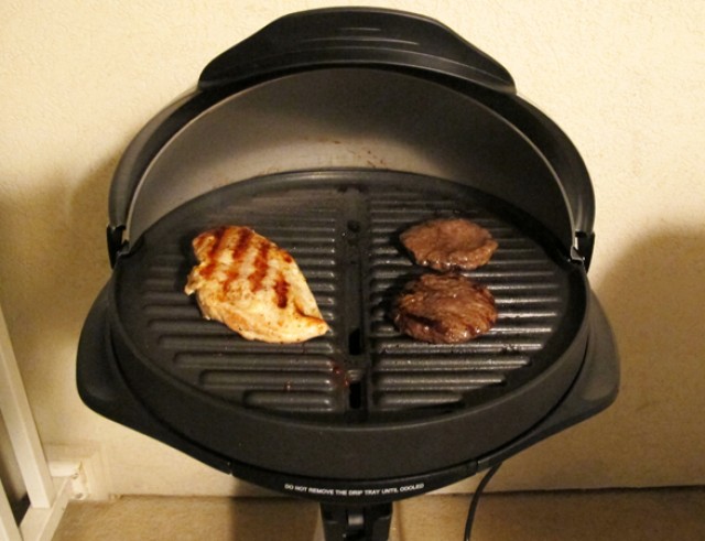 Grill elettrico con piastra circolare e cupola di chiusura durante la cottura dei cibi
