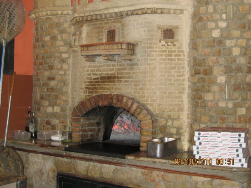 Bellissimo modello di forno a legna posizionato all'interno di una struttura in stile rustico